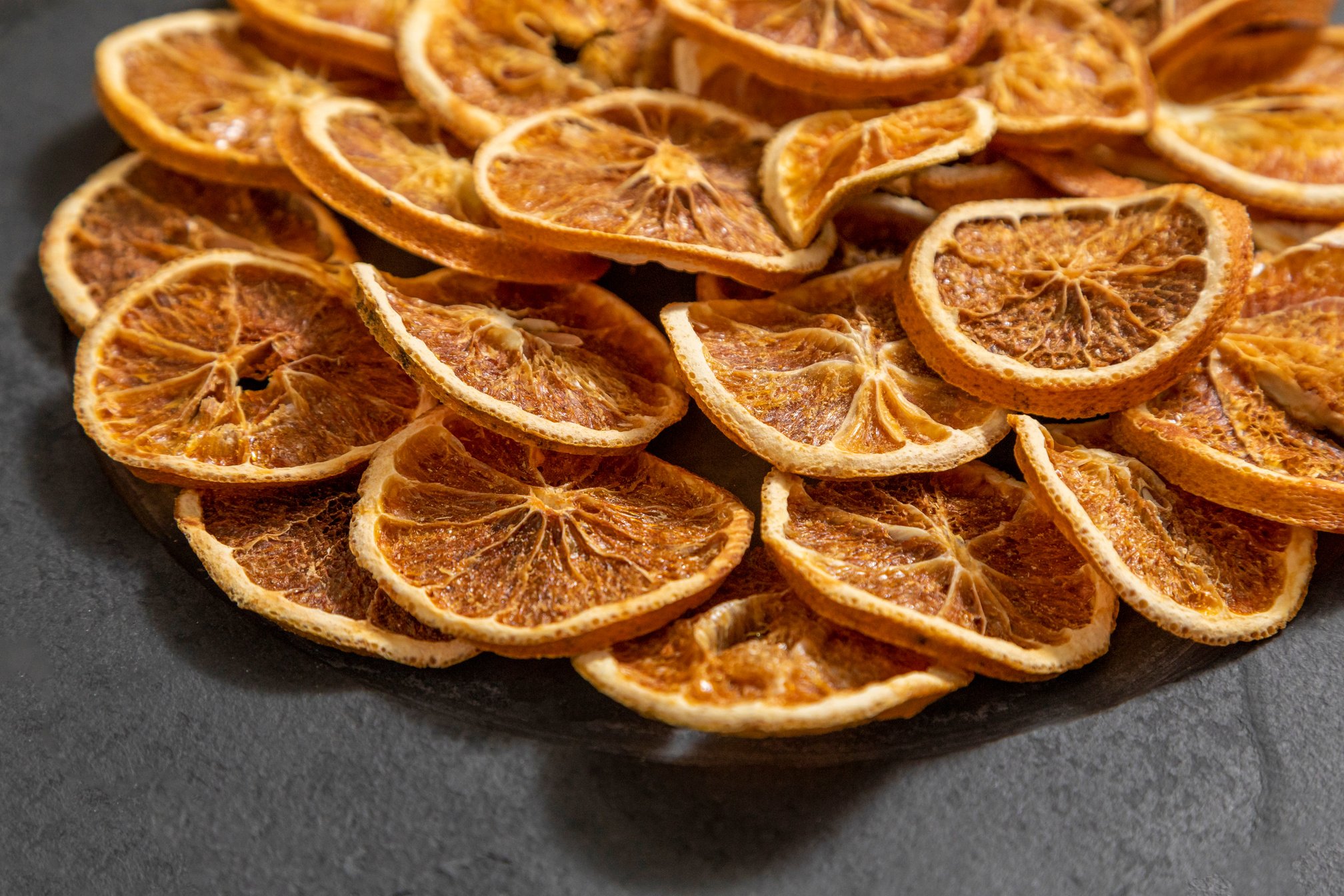 Slices of dehydrated orange on black stone. Selective focus